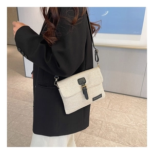Detail of woven straw crossbody bag featuring black leather strap and brand label