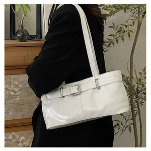 Dettaglio borsa sottobraccio bianca lucida con fibbia argento indossata su blazer nero