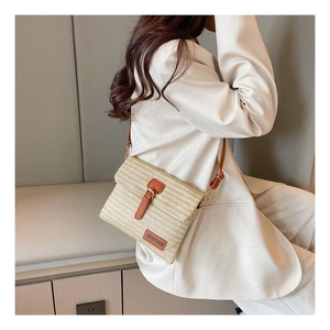 On-body shot of straw crossbody bag with brown leather trim and adjustable strap