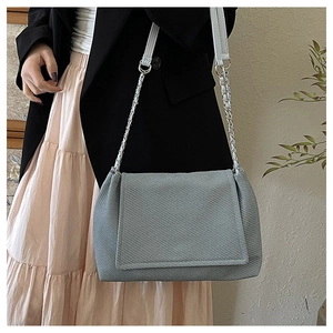 Detail of grey textured shoulder bag featuring silver chain strap and flap closure