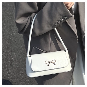 Détail du sac baguette blanc avec boucle noeud dorée et finition en cuir texturé
