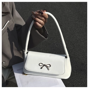 Détail d'un sac baguette en cuir blanc brillant avec boucle nœud dorée et bandoulière