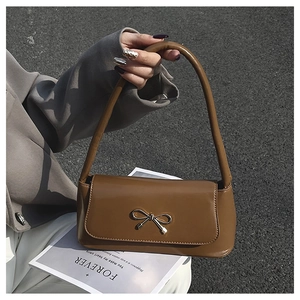 Sac baguette en cuir marron avec boucle nœud argenté porté à l'épaule en style urbain