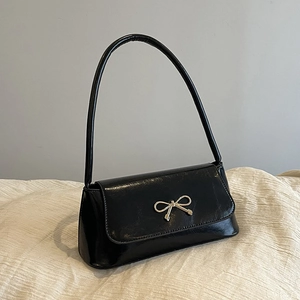 Gros plan d'un sac baguette noir vintage avec boucle nœud dorée sur lin