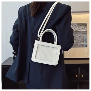 Detail view of a white leather crossbody bag with a large clear window and gold hardware