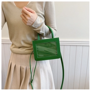 Detail of bright green crossbody bag with clear window shown on a fashion model
