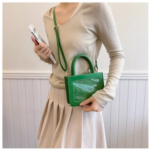Detail of green transparent PVC handbag with adjustable strap shown on model lifestyle view