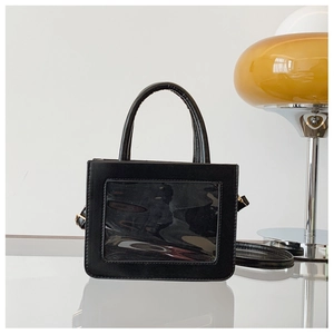 Detail of black glossy handbag with a unique transparent PVC window and round top handle