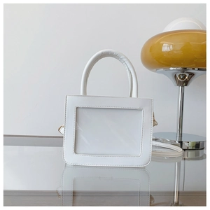 Detail view of white transparent ita bag showing the clear display window and top handle