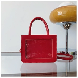 Detail view of the red ita bag featuring a transparent window and sleek leather texture