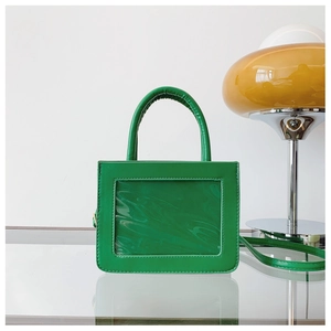 Detail view of a green square handbag with a transparent PVC window and top handle