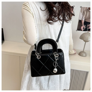 Detail of black quilted leather handbag with silver sphere charm and adjustable strap