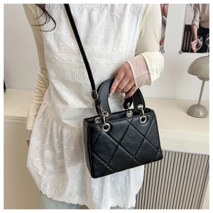 Detail of black quilted leather handbag with diamond stitching and silver eyelet accents
