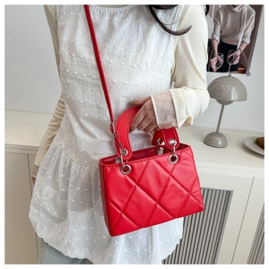 Detailed view of a red quilted handbag with silver rings and a sturdy top handle