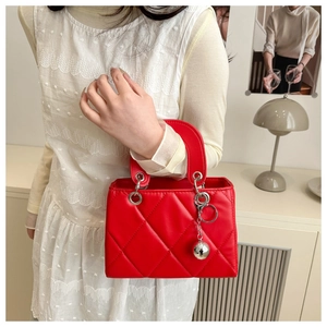 Detail of red quilted handbag with silver metal ball pendant and ring handle in a chic setting