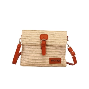 Straw messenger bag with brown leather strap and trim on a clean white background