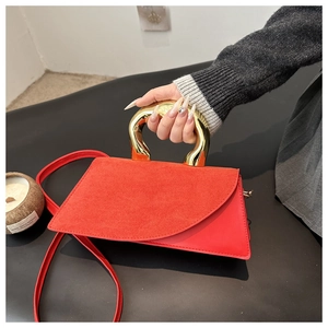 Detail of red leather crossbody bag with circular gold handle and suede texture flap
