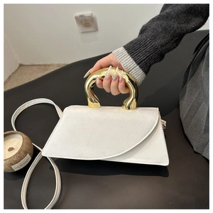 Detail of white irregular handbag with modern gold metal handle and slim shoulder strap