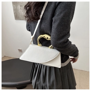 Detailed side view of white leather crossbody bag with gold sculptural metal handle