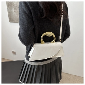 Chic white square bag with a unique gold irregular metal handle worn by a model