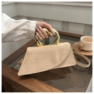 Detail of beige shoulder bag with unique golden metal handle and mixed leather texture