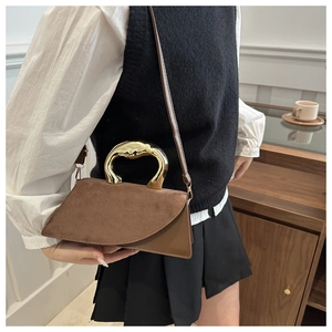 Detail of a brown asymmetrical handbag with unique gold liquid metal handle on a model
