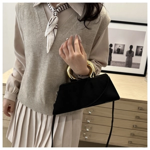 Detail of a black square handbag featuring unique double golden ring handles and a matte finish