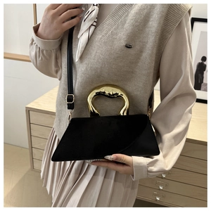 Detail of black asymmetrical bag featuring a unique gold metal handle and mixed textures