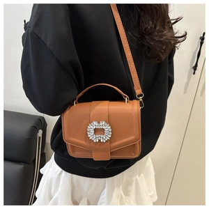 Detail of caramel brown crossbody bag with sparkling oversized rhinestone buckle