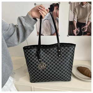 Detail view of large tote bag with repetitive M letter print and metal logo charm