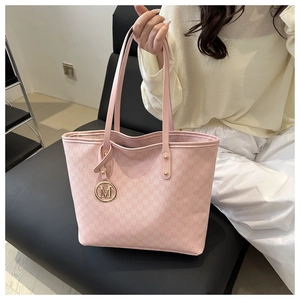 Detail of light pink tote bag featuring all-over M print and golden M metal charm