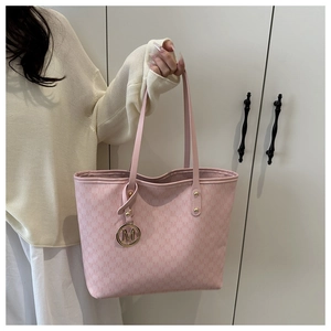 Detail of pink tote bag showing M-letter monogram pattern and gold metal pendant