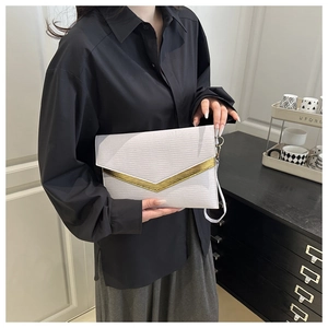 Detail of white envelope clutch with water ripple texture and gold V-shaped metal trim