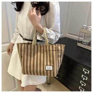 Detail of striped corduroy tote bag featuring camping patch and reinforced handle strap
