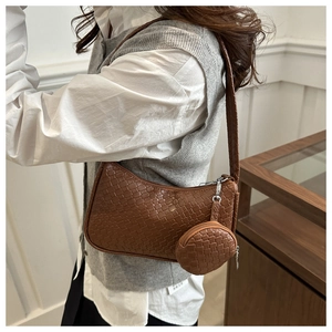 Close-up of brown woven shoulder bag texture with matching round coin purse charm