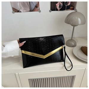 Dettaglio di pochette a busta nera con bordo a V dorato e finitura testurizzata