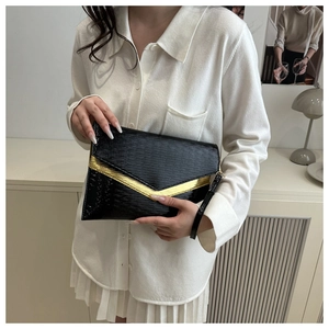 Detail of black envelope clutch featuring wavy Epi texture and gold V-shaped metal trim