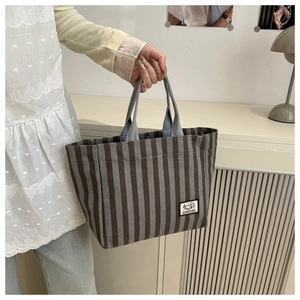 Detail of gray striped corduroy tote bag showing the Camping patch and fabric texture