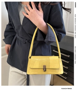 Détail du sac baguette jaune à motif crocodile avec fermoir rotatif en métal argenté