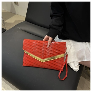 Dettaglio della pochette rossa con trama a coste e fibbia a V dorata per occasioni