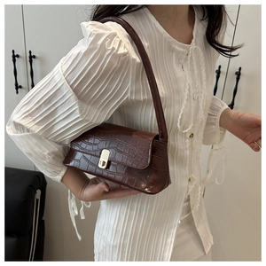 Détail du sac sous le bras marron foncé à motif crocodile avec boucle dorée sur chemise