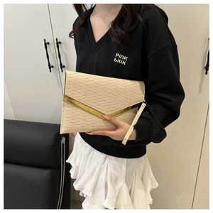Dettaglio della clutch crema con texture a onde e finitura in metallo dorato a forma di V