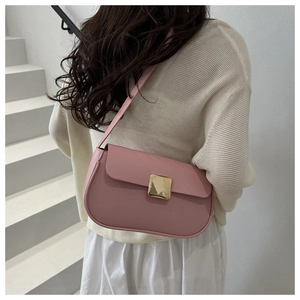 Sac sous le bras rose minimaliste porté par un modèle, avec boucle dorée et style élégant