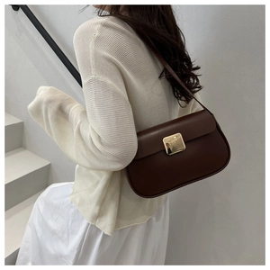 Detail of dark brown leather underarm bag with bright golden magnetic square clasp