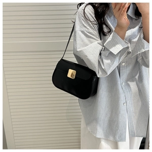 Detail of minimalist black leather underarm bag featuring a large gold square buckle lock