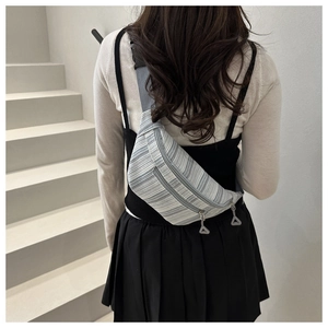 Close-up of striped nylon chest bag with dual zippers and adjustable grey strap details