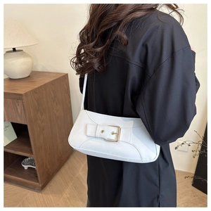 Minimalist white faux leather baguette bag with decorative buckle shown on shoulder