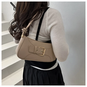 Detail of minimalist beige leather underarm bag with gold buckle and knotted shoulder strap