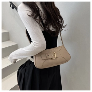 Close-up of beige minimalist underarm bag with gold square buckle on female model