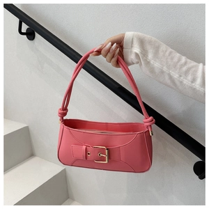 Detail of pink leather underarm bag featuring a gold buckle and knotted shoulder strap